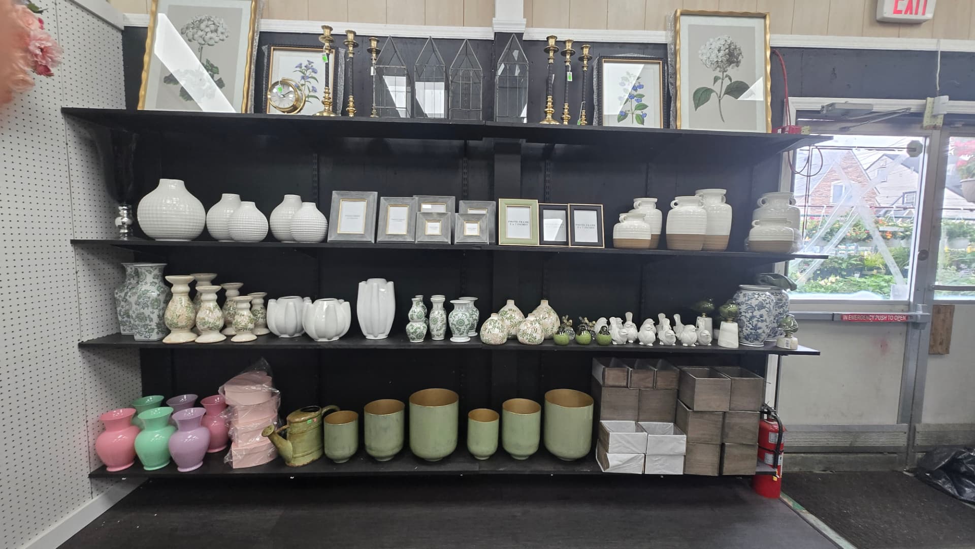 Ceramic vases, photo frames, candlesticks and botanical prints on black shelving